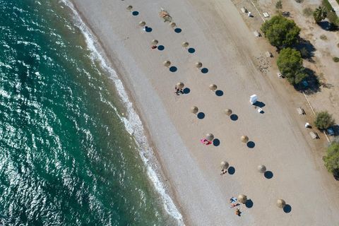 Griechenland: An einem Strand südlich von Athen stehen Sonnenschirme für Strandbesucher bereit