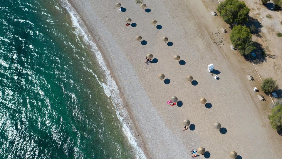 Griechenland: An einem Strand südlich von Athen stehen Sonnenschirme für Strandbesucher bereit