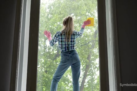 Frau putzt Fenster