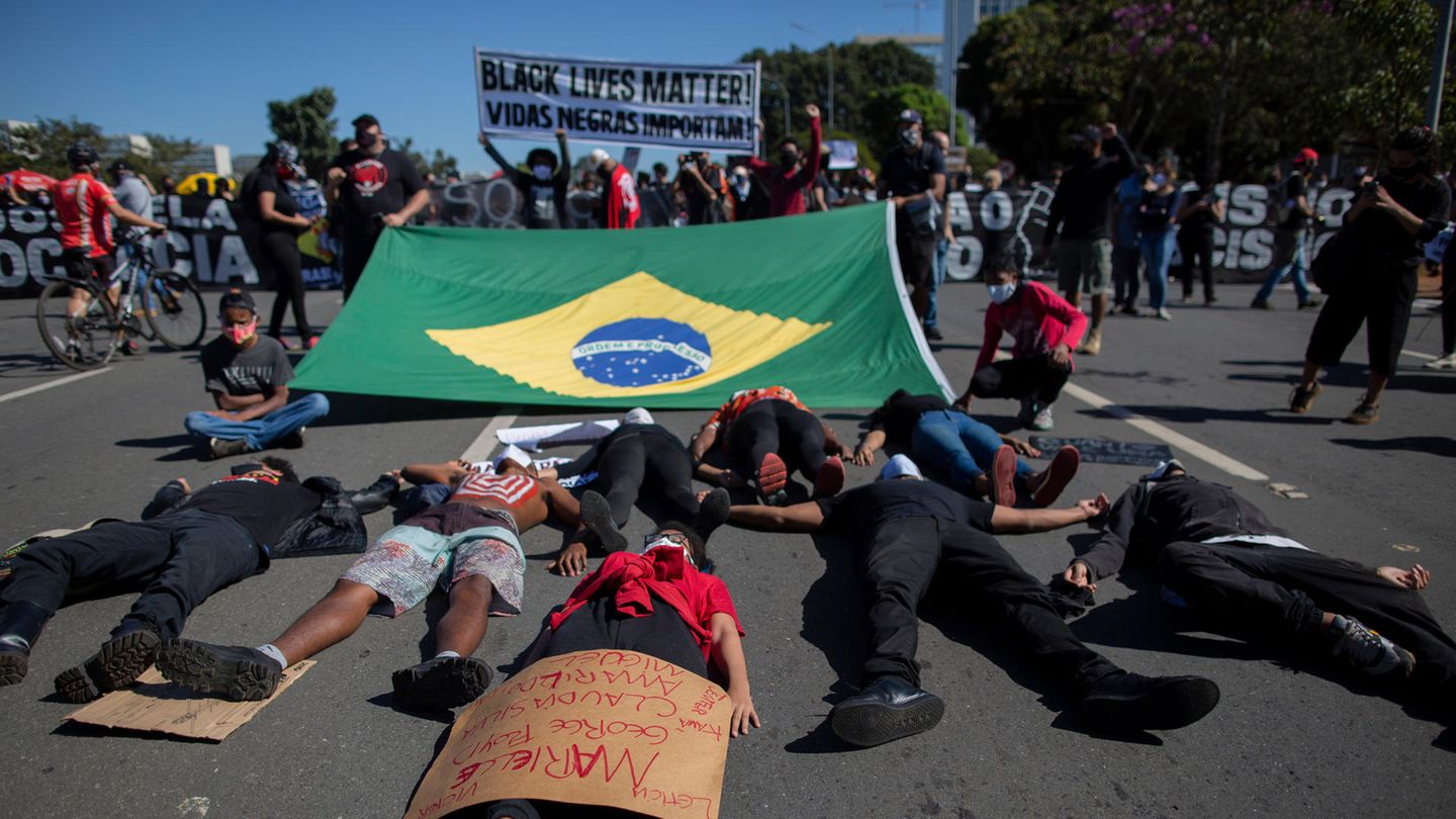 Brasilien: Junge Schwarze liegen hinter der Landesfahne auf dem Boden und symbolisieren den Tod schwarzer Menschen
