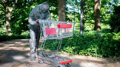 Eine Bronzefigur mit einem Einkaufswagen in den Händen steht in den Wallanlagen im Zentrum Bremens