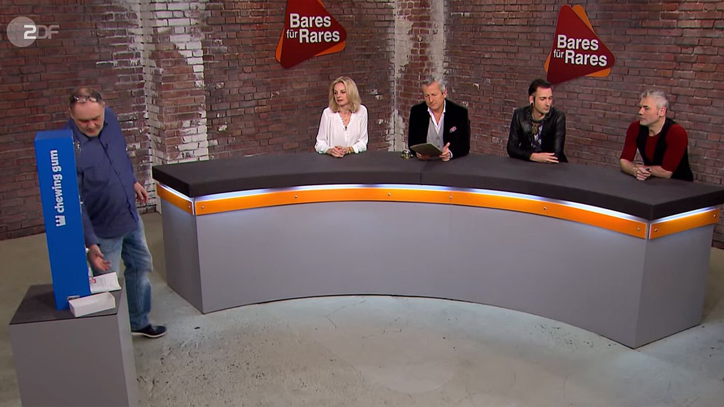 "Bares für Rares"-Händler Walter "Waldi" Lehnertz nimmt den Kaugummiautomaten in Augenschein. Susanne Steiger, Markus Wildhagen, Fabian Kahl und Christian Vechtel bleiben sitzen.