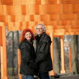 Das Paar steht lächelnd vor organgefarbenen Tüchern im Central Park in New York