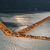 Orangefarbenes Gewebe schwimmt wegeartig auf einem See und bieten Fußgängern neuen Raum