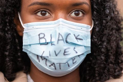 Auf dem Mundschutz einer schwarzen jungen Frau steht "Black Lives Matter"