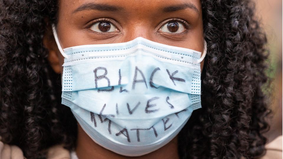 Auf dem Mundschutz einer schwarzen jungen Frau steht "Black Lives Matter" Auf dem Mundschutz einer schwarzen jungen Frau steht "Black Lives Matter"