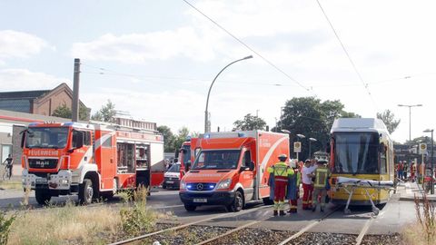 Einsatzkräfte der Feuerwehr stehen neben einer Straßenbahn.