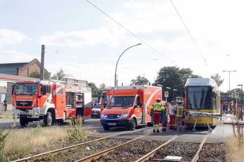 Einsatzkräfte der Feuerwehr stehen neben einer Straßenbahn.