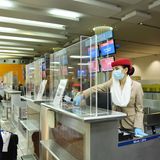 Arbeitsplatz Check-in: Die Mitarbeiterin am Flughafen Dubai wird durch eine Plexiglaskonstruktion am Counter geschützt.