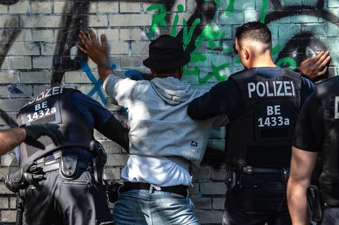 Polizeibeamte kontrollieren in einem Berliner Park einen Mann mit dunkler Hautfarbe als mutmaßlichen Drogendealer