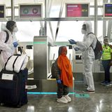 Check-in am Bangalore Airport in Indien: Diese Familie ist in Sicherheitskleidung geschlüpft, inklusive der Schuhe des Kindes.