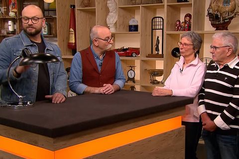 "Bares für Rares"-Experte Sven Deutschmanek nimmt die Leuchte von Ehepaar Janes in Augenschein. Moderator Horst Lichter bringt die Herkunft des Stückes in Erfahrung.