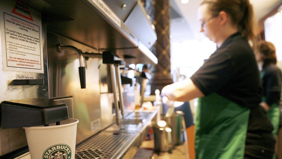 Mitarbeiterin von Starbucks macht einen Kaffee
