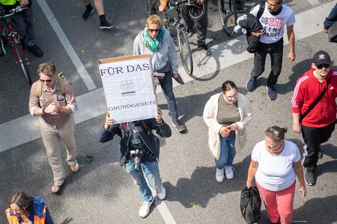 Ein Mann hält während einer Demonstration ein Schild, auf dem "Für das Grundgesetz" steht, hoch