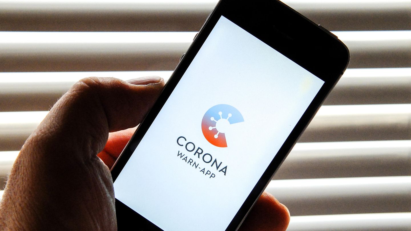 Auf dem Bildschirm eines Smartphones ist der Startschirm einer Corona-Warn-App zu sehen