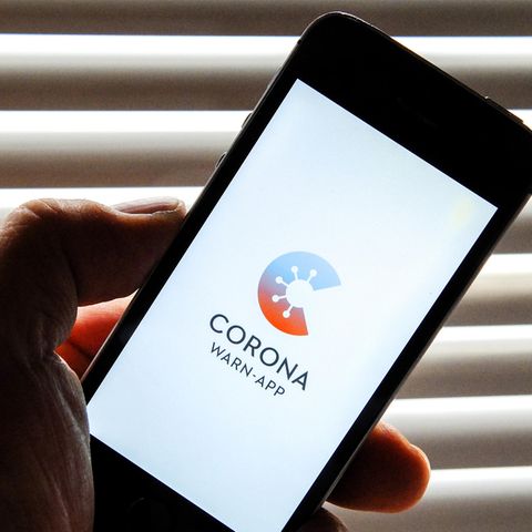 Auf dem Bildschirm eines Smartphones ist der Startschirm einer Corona-Warn-App zu sehen