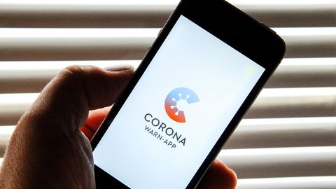 Auf dem Bildschirm eines Smartphones ist der Startschirm einer Corona Warn-App abgebildet