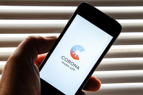 Auf dem Bildschirm eines Smartphones ist der Startschirm einer Corona Warn-App abgebildet