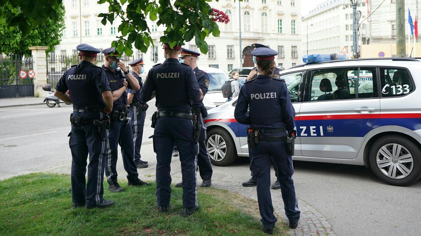 Polizisten stehen vor einem Polizeiwagen