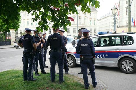 Polizisten stehen vor einem Polizeiwagen
