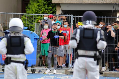 Polizisten sehen sich vor dem unter Quarantäne stehenden Wohnkomplex in Göttingen einer Gruppe junger Männer gegenüber