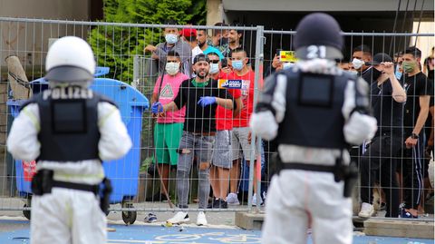 Polizisten sehen sich vor dem unter Quarantäne stehenden Wohnkomplex in Göttingen einer Gruppe junger Männer gegenüber