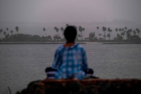 Eine Frau meditiert vor dem Panorama der Stadt San Juan, die von einer riesigen Wolke aus Saharastaub verhüllt ist