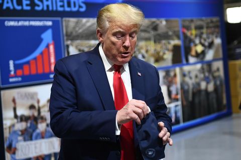 Donald Trump hantiert mit einer eingepackten Maske