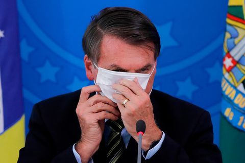 Bolsonaro versucht eine Maske aufzusetzen