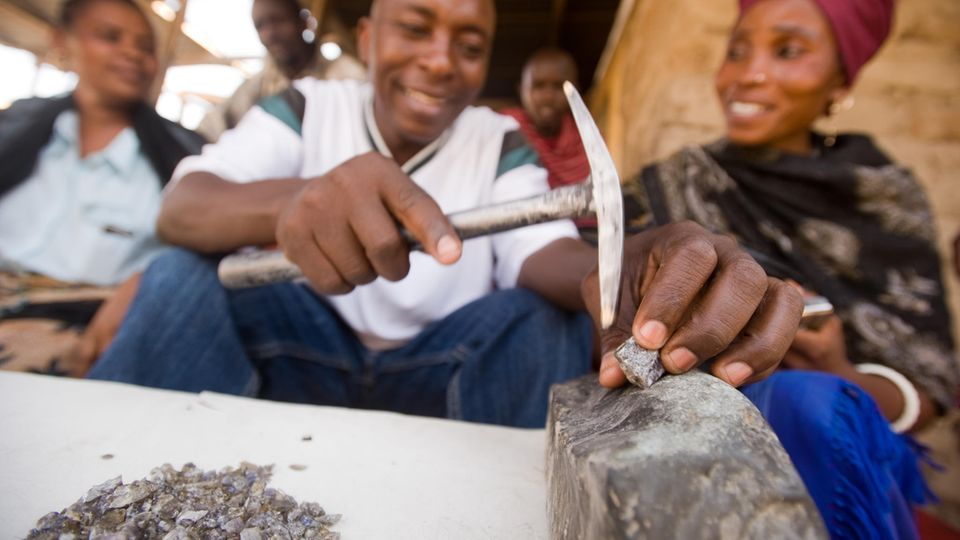 Ein Edelsteinhändler zerlegt auf einem Markt in Tansania einen Tansanit-Stein