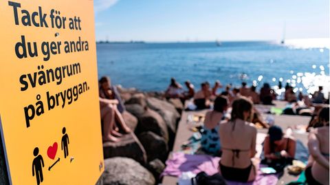 Ein Schild weist an einer vollen Badestelle in Malmö darauf hin, Abstand zu halten