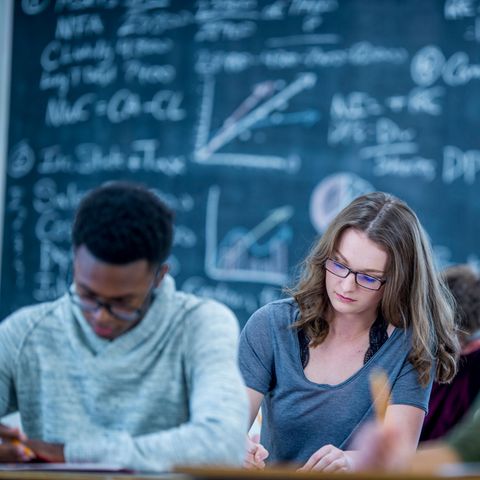 Schüler sitzen vor einer Tafel mit Formeln