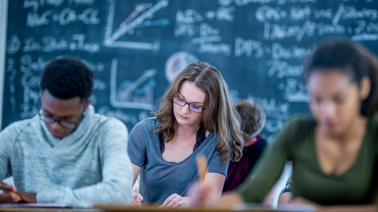 Schüler sitzen vor einer Tafel mit Formeln