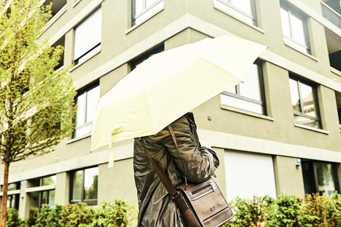 Jasmin mit Regenschirm vor einem Wohnblock
