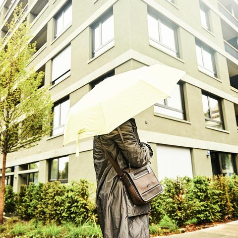 Jasmin mit Regenschirm vor einem Wohnblock