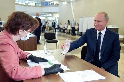 Wladimir Putin, Präsident von Russland, zeigt einer Mitarbeiterin der Wahlkommission seinen Pass in einem Wahllokal