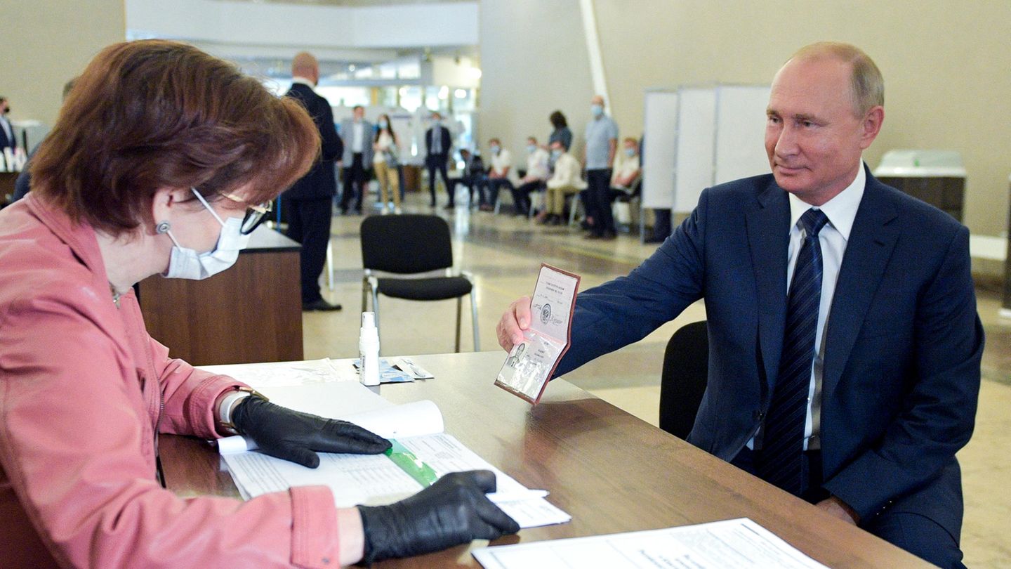 Wladimir Putin, Präsident von Russland, zeigt einer Mitarbeiterin der Wahlkommission seinen Pass in einem Wahllokal