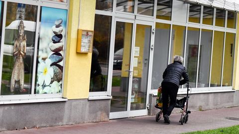 Eine Frau mit einem Rollator geht auf eine Gehweg