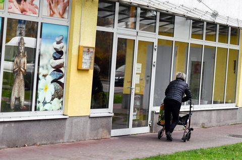 Eine Frau mit einem Rollator geht auf eine Gehweg