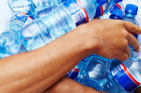 Mann hält Wasserflaschen im Arm