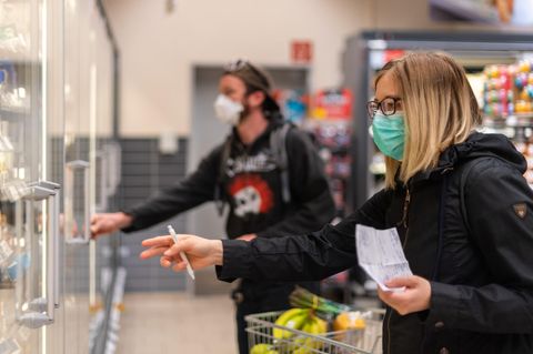 Kunden gehen in einem Supermarkt einkaufen und tragen dabei Mundschutz
