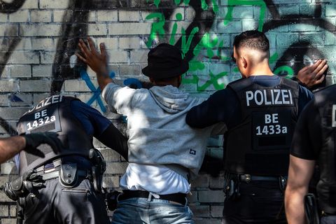 Polizisten kontrollieren in einem Berliner Park einen Mann mit dunkler Hautfarbe als mutmaßlichen Drogendealer