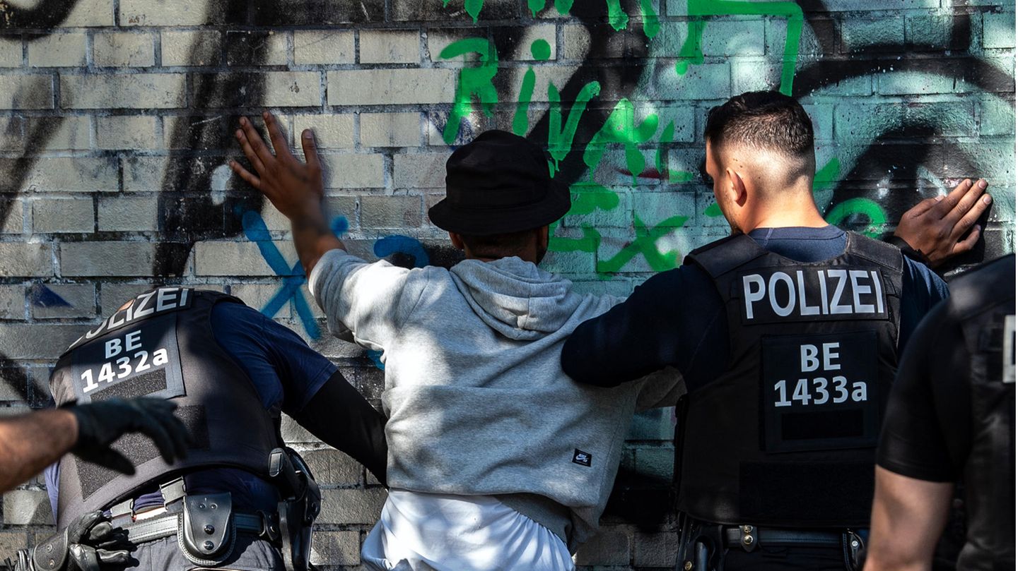 Polizisten kontrollieren in einem Berliner Park einen Mann mit dunkler Hautfarbe als mutmaßlichen Drogendealer