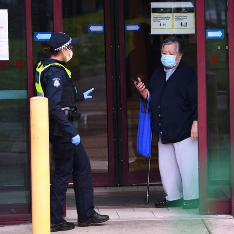 Eine Polizistin spricht mit einer Bewohnerin am Eingang einer Wohnsiedlung