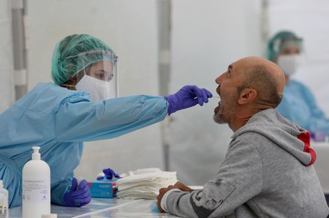 Gesundheitsamts-Mitarbeiterin macht einen Abstrich im Rachen eines Mannes