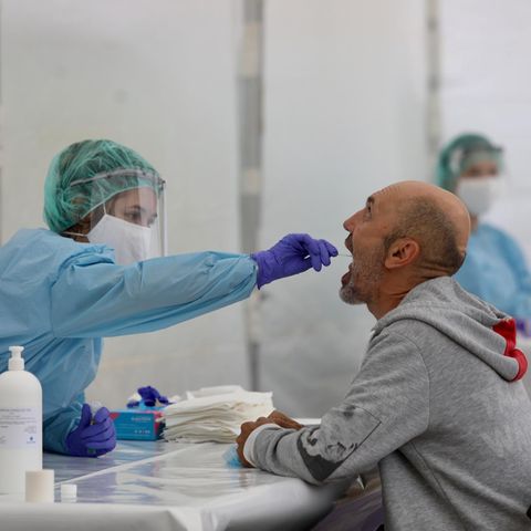 Gesundheitsamts-Mitarbeiterin macht einen Abstrich im Rachen eines Mannes