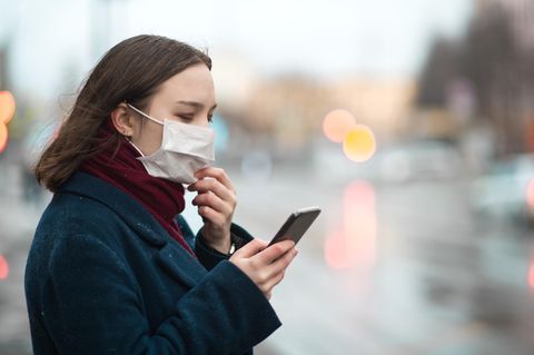 Eine Frau mit Mundschutz und Smartphone