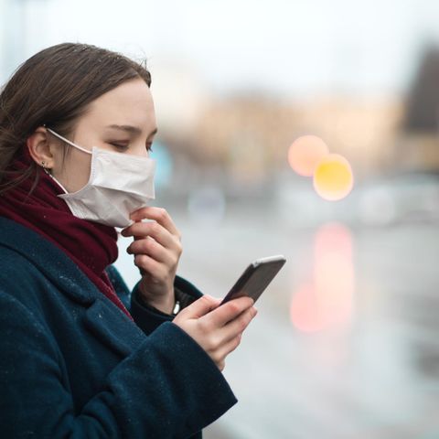Eine Frau mit Mundschutz und Smartphone
