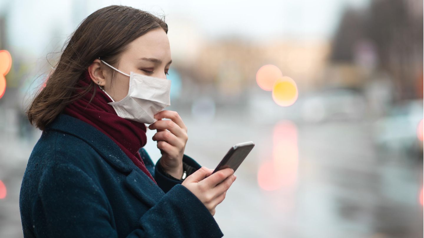 Eine Frau mit Mundschutz und Smartphone