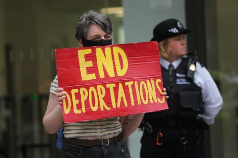Demonstrantin protestiert mit Schild "End Deportations" gegen Abschiebungen